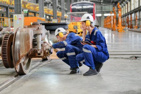 Foto de Ingenieros inspeccionando locomotoras en instalaciones de ingeniería ferroviaria - Imagen libre de derechos