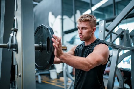 Photo for Male athlete exercising in the gym, lifting weights, pulling joints. - Royalty Free Image