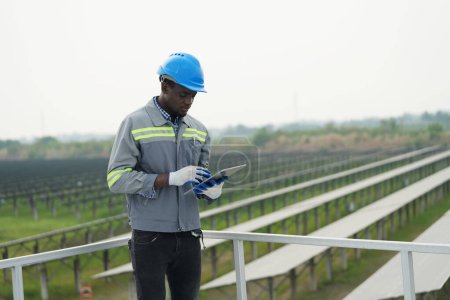 Foto de Ingeniero electricista con casco trabajando en una granja fotovoltaica, equipos de control y mantenimiento con instrumentos en la industria de energía solar. - Imagen libre de derechos