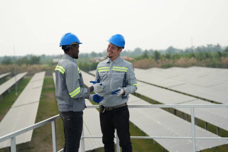 Téléchargez les photos : Ingénieurs électriciens travaillant dans une ferme photovoltaïque, équipement de contrôle et d'entretien avec des instruments à l'énergie solaire industrielle. - en image libre de droit
