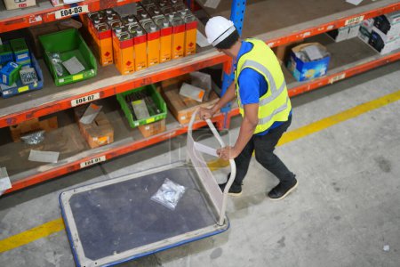 Foto de Trabajador trabajando en un almacén grande. cajas de verificación envueltas con plástico en una plataforma de madera lista para enviar al cliente - Imagen libre de derechos