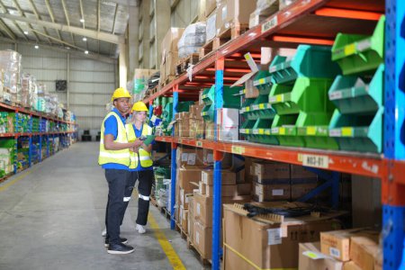 Photo for Workers working in large warehouse, checking wrapped boxes - Royalty Free Image
