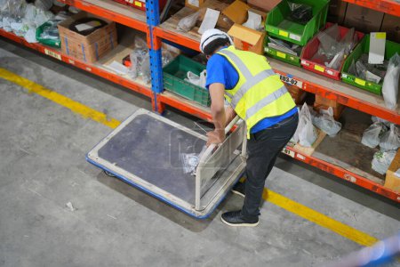 Foto de Trabajador trabajando en un almacén grande. cajas de verificación envueltas con plástico en una plataforma de madera lista para enviar al cliente - Imagen libre de derechos