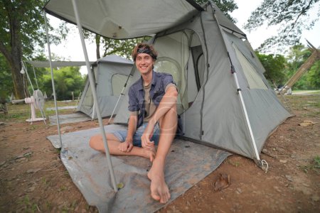 Téléchargez les photos : Jeune touriste mâle se reposant près de la tente dans le camp - en image libre de droit