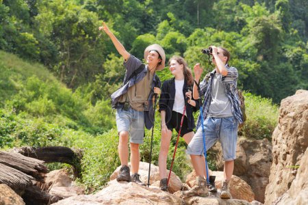 Photo for Hikers walking along a trail on a mountain with hiking sticks. Adventure, travel, tourism, hike and people concept. Group of smiling friends with backpacks outdoors. - Royalty Free Image