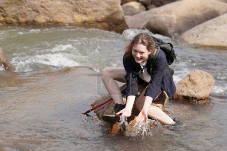 Foto de Aventura, viajes, turismo, senderismo y concepto de personas. joven mujer con mochilas sentado en la roca en el río - Imagen libre de derechos