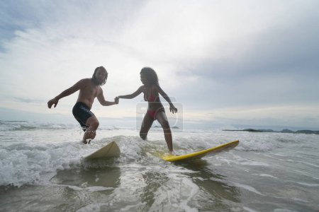 Foto de Pareja feliz surfeando juntos en la playa con tabla de surf en Pattaya, Tailandia. - Imagen libre de derechos