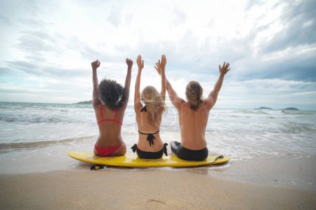 Téléchargez les photos : Jeunes femmes et hommes surfeurs profitant de leur temps à la plage - en image libre de droit