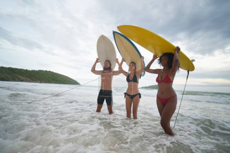 Téléchargez les photos : Jeunes femmes et hommes surfeurs profitant de leur temps à la plage - en image libre de droit