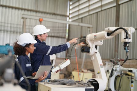 Foto de Ingenieros industriales multirraciales que trabajan en la fábrica automatizada de producción robótica de IA, nuevo concepto de tecnología industrial. - Imagen libre de derechos