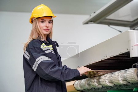 Photo for Industrial worker indoors in factory. Young technician with orange hard hat. Smart Caucasian factory worker wearing hardhat and working in power plant. - Royalty Free Image