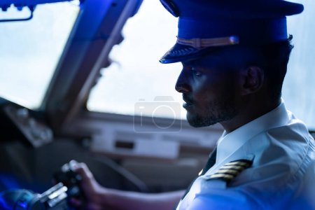Photo for Happy young pilot in professional uniform at airport. Male pilot sitting in airplane cockpit - Royalty Free Image