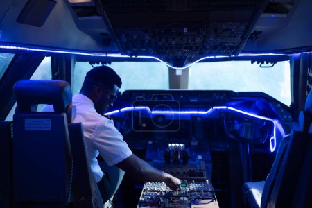 Téléchargez les photos : Heureux jeune pilote en uniforme professionnel à l'aéroport. Pilote assis dans le cockpit de l'avion - en image libre de droit
