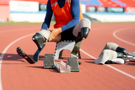 Asian para-athletes with prosthetic blades sprint on a running track at stadium.