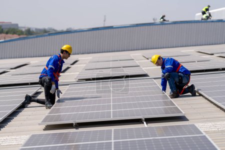 Foto de Ingenieros profesionales revisando el techo solar en la azotea de fábrica bajo la luz solar. Ingenieros con trabajo de servicio de energía eléctrica renovable - Imagen libre de derechos
