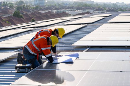 Foto de Ingenieros profesionales revisando el techo solar en la azotea de fábrica bajo la luz solar. Ingenieros con trabajo de servicio de energía eléctrica renovable - Imagen libre de derechos