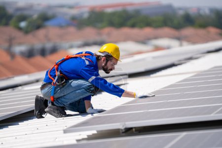 Téléchargez les photos : Ingénieur professionnel vérifiant panneau de toit solaire sur le toit de l'usine sous la lumière du soleil. Ingénieur ayant un emploi de service d'énergie électrique renouvelable éco - en image libre de droit