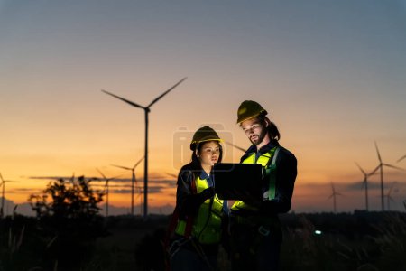 Téléchargez les photos : Deux ouvriers industriels multiraciaux examinant des éoliennes. Zone rurale avec éco-ferme de production énergie verte propre - en image libre de droit