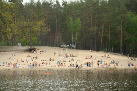 Photo for Crowd of people sunbathing on the sandy beach of a lake, swimming in the water. May 12, 2021. Pushcha Vodytsia city park, Kyiv, Ukraine - Royalty Free Image