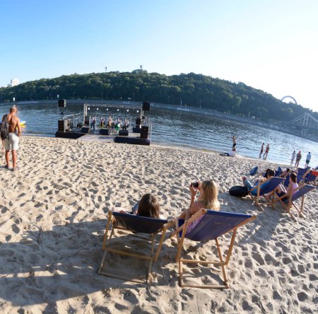 Foto de Gente sentada en una playa y tomando el sol. Festival de Yoga y Cultura Védica Vedalife-2018. 25 de julio de 2018. Kiev, Ucrania - Imagen libre de derechos