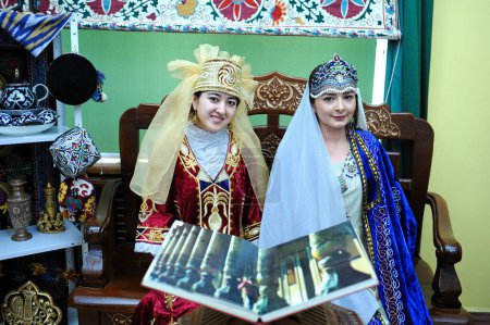 Foto de Mujeres jóvenes asiáticas en trajes nacionales tayikos presentando stand de Tayikistán. Festival de la cultura oriental. 20 de marzo de 2018. Kiev, Ucrania - Imagen libre de derechos