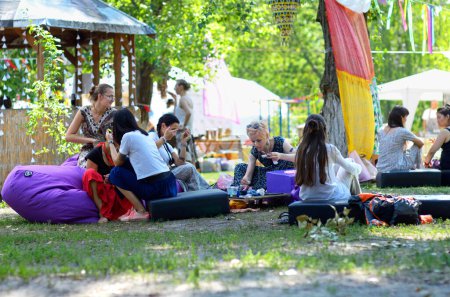 Foto de Mujeres jóvenes sentadas en bolsas de frijoles en un campamento y relajadas. Festival de Yoga y Cultura Védica Vedalife. 7 de agosto de 2017. Kiev, Ucrania - Imagen libre de derechos