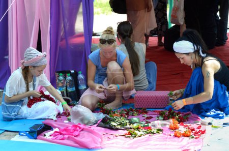 Foto de Mujeres vestidas con ropa oriental sentadas en el suelo y haciendo decoraciones florales. Fest Vedalife. 7 de agosto de 2017. Kiev, Ucrania - Imagen libre de derechos