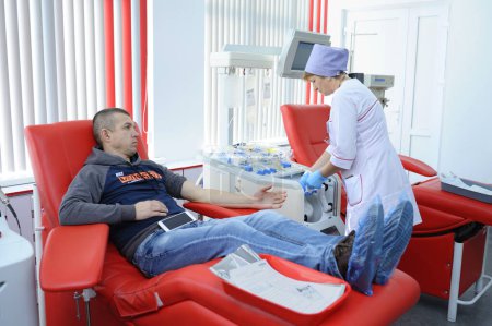 Photo for Nurse taking blood from the vain of the donor, hypodermic needle, tubes, container with blood. City municipal blood transfusion station. April 5, 2022. Kyiv, Ukraine - Royalty Free Image