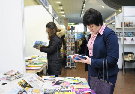 Photo for Women buyers standing in front of a bookshop counter and reading new published books. Book Fair. December 14, 2017. Kyiv, Ukraine - Royalty Free Image