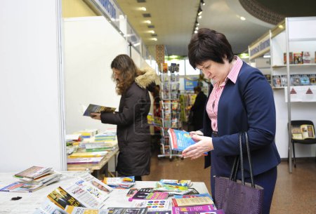 Photo for Women buyers standing in front of a bookshop counter and reading new published books. Book Fair. December 14, 2017. Kyiv, Ukraine - Royalty Free Image