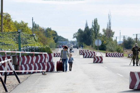 Foto de Mujer con una bolsa y un niño cruzando la frontera entre Ucrania y Rusia en el paso fronterizo Kalanchak. 20 de septiembre de 2017. Región de Kalanchak, Provincia de Khersonskaya, Ucrania - Imagen libre de derechos