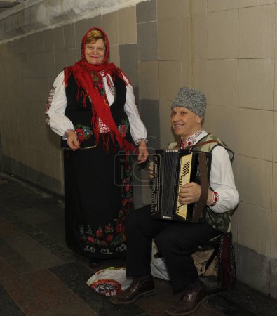 Photo for An old man and woman, street musicians, dressed in national Ukrainian costumes playing bayan and singing in the underpass. October 5, 2019. Kiev, Ukraine - Royalty Free Image