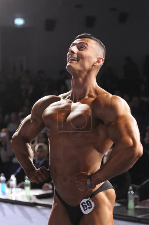 Photo for Muscly man posing on podium with strange look on his face, bodybuilding. Kyiv championship among amateurs. December 5, 2019. Kyiv, Ukraine - Royalty Free Image