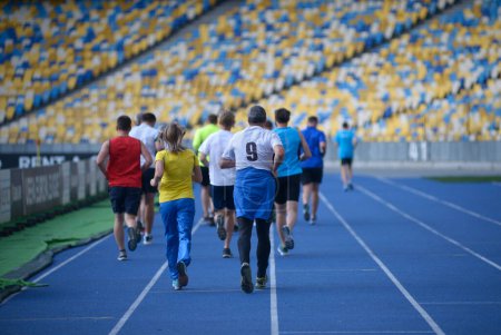 Photo for Group of people running on tracks of the stadium in the evening light. - Royalty Free Image