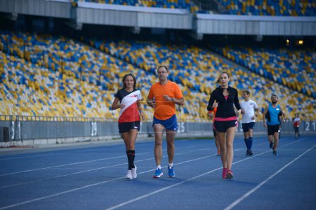 Photo for Group of people runners running on tracks of the stadium in evening light. October 14, 2019. Olympic National Sports Complex, Kiev, Ukraine - Royalty Free Image