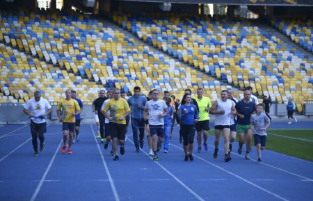 Photo for Group of people runners running on tracks of the stadium in evening light. October 14, 2019. Olympic National Sports Complex, Kiev, Ukraine - Royalty Free Image