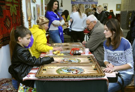 Photo for People playing backgammon, boy and woman on a foreground. Outlook world culture festival. October 27, 2018. Kiev, Ukraine - Royalty Free Image