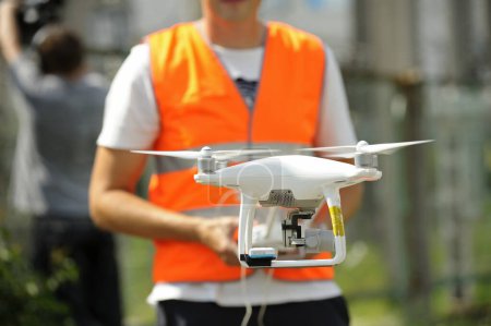 Foto de Pro quadcopter con cámara a bordo volando, operador controlándolo en el fondo - Imagen libre de derechos