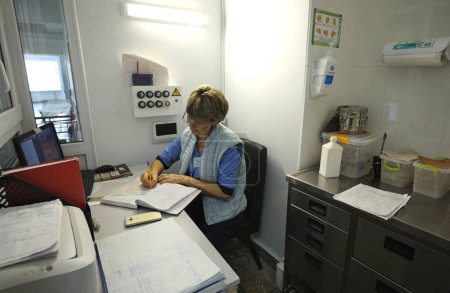 Foto de De guardia en un hospital. Enfermera sentada en una enfermería y escribiendo en un periódico. 12 de enero de 2019. Clínica regional de Kiev 1. Kiev, Ucrania - Imagen libre de derechos