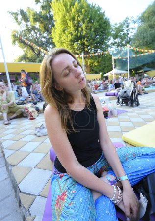 Foto de Niña sentada en karemat en el cine al aire libre y rezando. Fiesta del Vedalife. 10 de julio de 2021. Kiev, Ucrania - Imagen libre de derechos