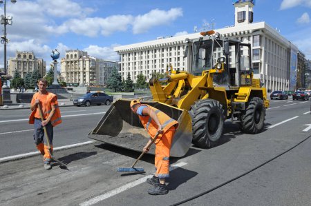 Téléchargez les photos : Les travailleurs asphalte réparer la route sur la rue à l'aide de pelles et chargeur frontal. 7 août 2021. Kiev, Ukraine - en image libre de droit