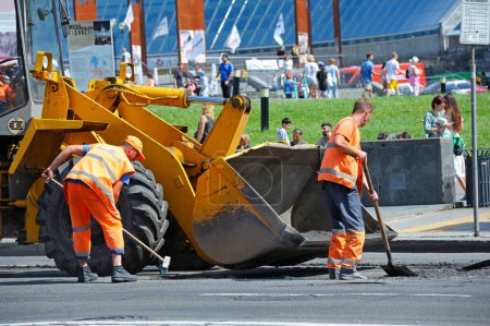 Téléchargez les photos : Les travailleurs asphalte réparer la route sur la rue à l'aide de pelles et chargeur frontal. 7 août 2021. Kiev, Ukraine - en image libre de droit