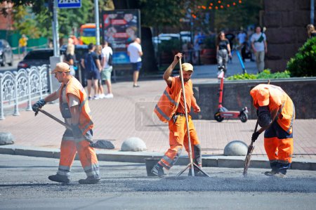 Téléchargez les photos : Travailleurs asphalte réparer la route sur la rue de la ville. 7 août 2021. Kiev, Ukraine - en image libre de droit