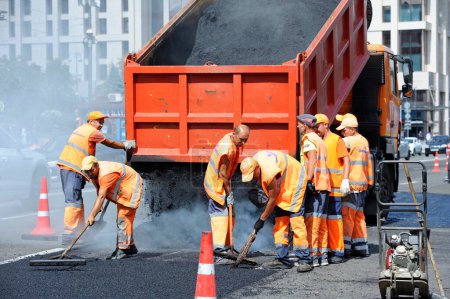 Téléchargez les photos : Les travailleurs asphalte réparer la route dans la rue en utilisant des pelles et camion à benne basculante. 7 août 2021. Kiev, Ukraine - en image libre de droit