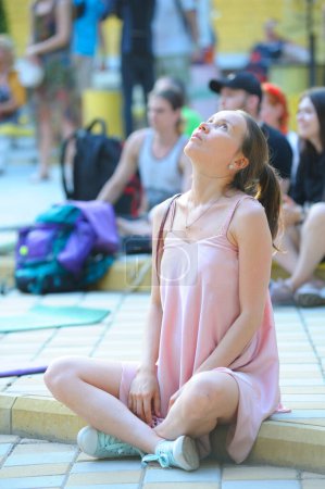 Foto de Niña sentada en karemat en el cine al aire libre y rezando. Fiesta del Vedalife. 10 de julio de 2021. Kiev, Ucrania - Imagen libre de derechos