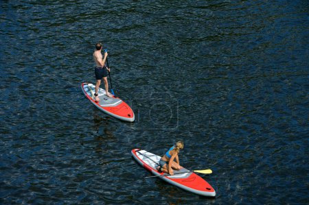 Photo for Young man and woman rowing SUP boards on the water, training. June 10, 2021. Hydropark, Kyiv Ukraine - Royalty Free Image