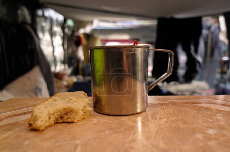 Tasse en métal et un morceau de pain placé sur une table dans une cellule. Centre de détention de Lukyanovskaya