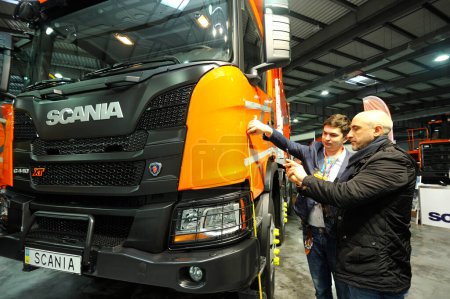 Photo for Men measuring sizes of a new model of a dump truck Scania parked on a stand. Exhibition Heavy Duty 2019. March 20, 2019. Berezovka, Ukraine - Royalty Free Image