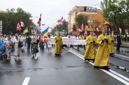 Photo for Crowd of people and orthodox priests in golden cassocks walking down the street of city. Ukrainian Orthodox Church of Kyiv Patriarchate, cross procession. July 28, 2019. Kyiv, Ukraine - Royalty Free Image