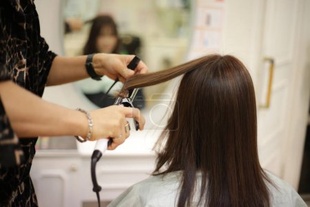 Photo for Male hairdresser ironing a woman's hair - Royalty Free Image